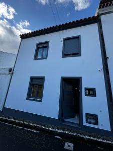 a white house with a black door and windows at Casa da Vila in Vila Franca do Campo