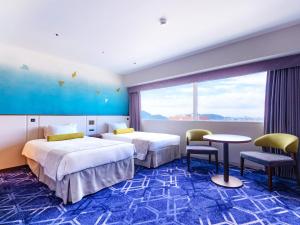 een hotelkamer met twee bedden en een tafel en stoelen bij Hotel Nikko Himeji in Himeji