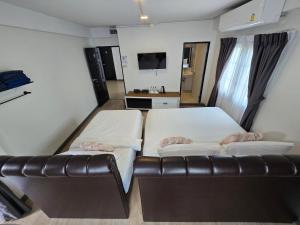 a bedroom with two beds and a leather couch at Charma Home Watket in Chiang Mai +28 photos