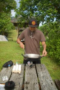 a man cooking food on a pan on a table at Johanna's Farm and Camping Ground in Inabanga