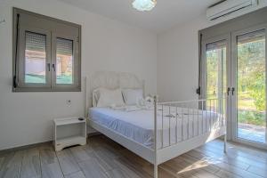 a white bedroom with a bed and a window at Cretan Blue Bungalow Chania in Chania +12 photos