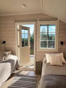 a bedroom with two beds and a sliding glass door at Villa Levi Snowlight, Modern & cozy cabin & 2 ski passes in Kittilä