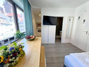 ein Wohnzimmer mit einem TV und einem Tisch mit Blumen in der Unterkunft Cozy Studioapartment in Würzburg