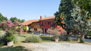 a large red house with trees and flowers in a yard at Country House Bucaneve in Rovolon