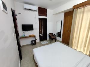 a bedroom with a white bed and a television at Hotel Sea Moon in Cox's Bazar