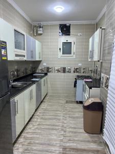 a large kitchen with white cabinets and a trash can at Maat apartment in Luxor