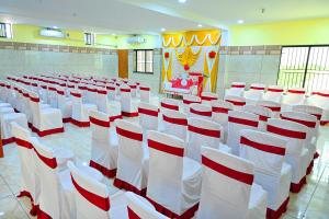 a room with rows of white chairs with red accents at Sigappi Residency in Pudukkottai
