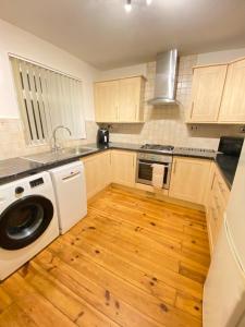 a kitchen with a washing machine and a wooden floor at 3 Bedroom Terraced House with Free Parkings, Close to City Centre and Transportation Links, at Gateshead, Newcastle upon Tyne in Gateshead