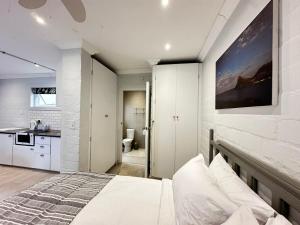 a white bedroom with a bed and a kitchen at Harbor View Cottage in Hout Bay