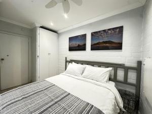 a bedroom with a bed with two pictures on the wall at Harbor View Cottage in Hout Bay