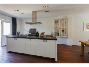 a kitchen with white cabinets and a black counter top at Central Domburg Apartment in Domburg +21 photos