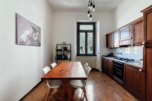 Una cocina con una mesa de madera y sillas blancas. en Liberty Home by Quokka 360 - period apartment in Como, en Como