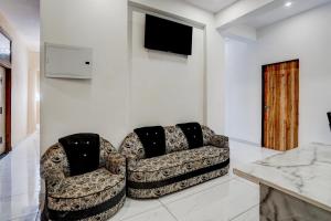 a living room with two chairs and a television at Super Collection O Iskcon Temple Mansarovar Formerly Chinar Inn in Jaipur