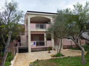 ein rosafarbenes Haus mit Bäumen davor in der Unterkunft Apartments in Starigrad-Paklenica 41707 in Starigrad-Paklenica