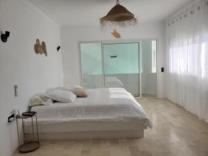 a white bedroom with a bed and a glass wall at Maison Dar Khalil in Hammamet +19 photos