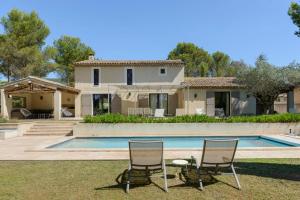 a house with a swimming pool and two chairs at Bastide Blanche Villa with swimming pool and pétanque court in Lourmarin in Lourmarin