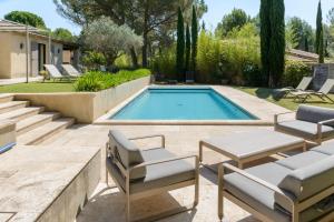 a swimming pool with two chairs and a table at Bastide Blanche Villa with swimming pool and pétanque court in Lourmarin in Lourmarin
