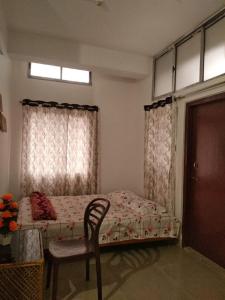 a bedroom with a bed and a chair and a window at Globalindia Homestay in Guwahati