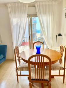 une table en bois avec des chaises et un bol bleu dessus dans l'établissement Fantástico apartamento en Sant Antoni, a solo 1 minuto de la playa, à Calonge