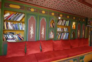 a red couch in a library with shelves of books at Kybele Hotel in Istanbul