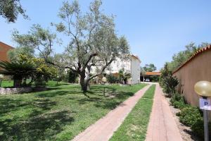 a brick path in a yard with a tree at Villa Sa Marchesa - Sa Murta Apartments in Solanas