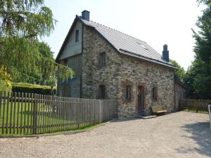 an old stone house with a fence in front of it at Chalet Retreat with Sauna in Robertville