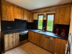 a kitchen with wooden cabinets and a stove top oven at Chalet Retreat with Sauna in Robertville