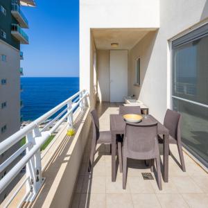 a balcony with a table and chairs and the ocean at 16th Floor with Pool & 180 Sea Views by QuickTrips in Sliema