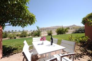 a white table with white chairs and a bottle of wine at Almog Hotel in Almog