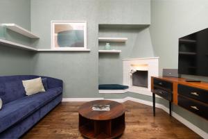 Una sala de estar con un sofá azul y una chimenea. en Fossi Street Central Apartment, en Florencia