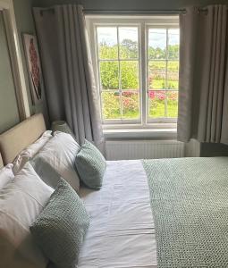 a bedroom with a bed with pillows and a window at Detach Sandstone Cottage, Sleeps 6, 2 x King Size, 2 x Singles in Lower Beeding