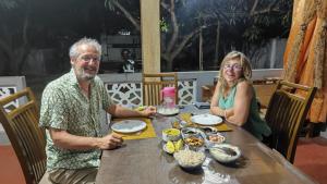 a man and a woman sitting at a table at Enoch Guest House in Mannar
