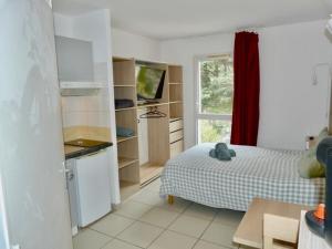 a bedroom with a bed and a kitchen with a window at Le Clos d'AIX Studio 113 in Aix-en-Provence