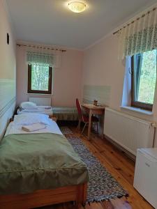 2 letti in una camera con scrivania e tavolo di Noclegi Kurpie, Pokoje Gościnne, Wyżywienie, Catering, AGRO ELA a Skorka