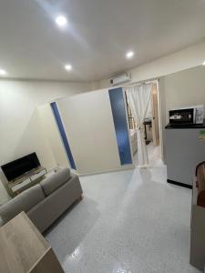 a living room with a couch and a tv at Sairin 1 bedroom BTS Udomsuk in Bangna