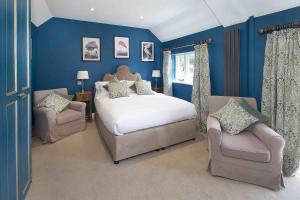 a blue bedroom with a bed and two chairs at Hill Farm in Oxford