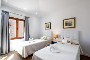 two beds in a white room with a window at Horta 55 in Pollença +29 photos