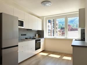 a kitchen with white cabinets and a large window at Bright modern apartment, 100m from Sarajevo City Hall & Old Town in Sarajevo