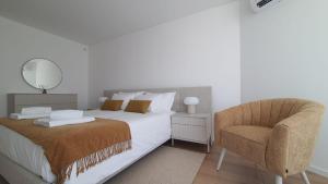 Un dormitorio blanco con una cama y una silla. en DelMar WaterFront DL, en Olhão 42 fotos más