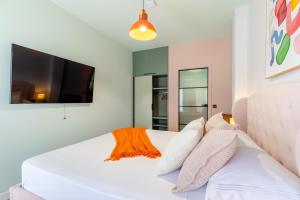 1 cama blanca con almohadas y TV de pantalla plana. en Charm Beach Retreat, en Alicante