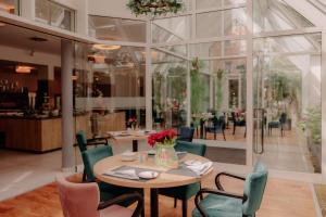 a dining room with a table with flowers and chairs at Stadthotel Borken by Hackmann in Borken