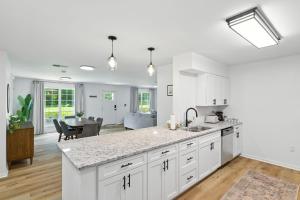 a kitchen with white cabinets and a living room at Family Getaway 9BR Open-Concept Retreat home in Winston-Salem