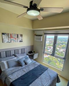a bedroom with a bed with a ceiling fan and a window at Sky Pad Avida Abreeza Davao in Davao City