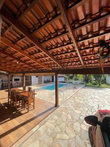 a patio with a wooden roof with a table and chairs at Rancho Monte Verde in Elói Mendes
