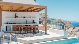 a villa with a swimming pool and a woman standing on a house at The Villas by Santo Collection in Oia