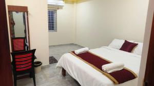 a bedroom with a white bed and a chair at Rajeshwari Tower & Residency in Tiruvannāmalai