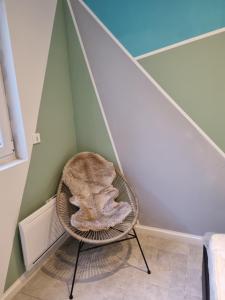 una silla de mimbre en un rincón de una habitación en VALSCOSY parking - Activités illégales interdite, en Valenciennes 1 foto más