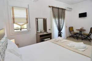 a white bedroom with a bed and a window and a table at Inanthi in Potos