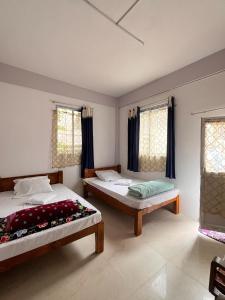 a bedroom with two beds and two windows at Hams Cherrapunji in Cherrapunji +19 photos