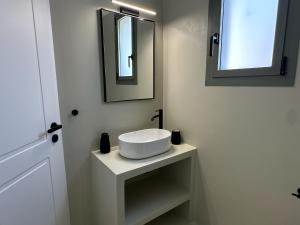 a bathroom with a white sink and a mirror at Ammos Andros Accommodation in Khónai